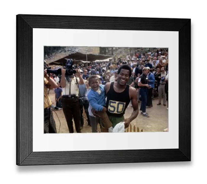 Framed Print : Lee Evans. American sprinter Lee Evans (1947 - 2021) holding his son Keith Framed Print : Lee Evans. American sprinter Lee Evans (1947 - 2021) holding his son Keith