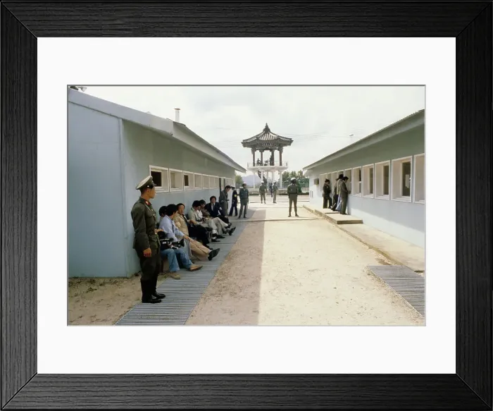 Framed Print : Panmunjom. Members of the press sitting in the shade of a building in Panmunjom