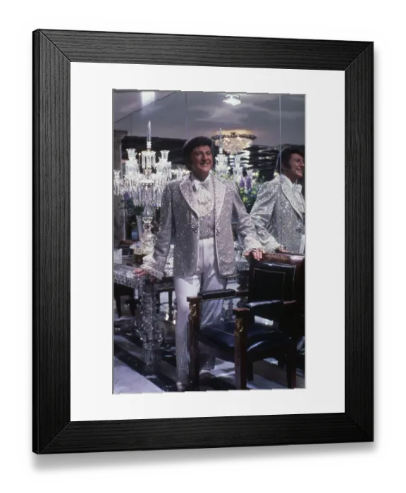Framed Print : Liberace. Singer Liberace wearing a silver sequined outfit at home