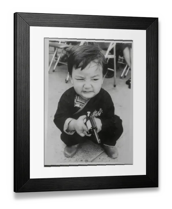 Framed Print : Grimacing Child Holding a Plastic Gun