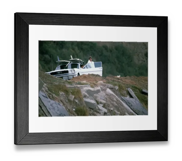 Framed Print : Surf Car. A surfboard mounted on the roof rack of a car at an unspecified Framed Print : Surf Car. A surfboard mounted on the roof rack of a car at an unspecified