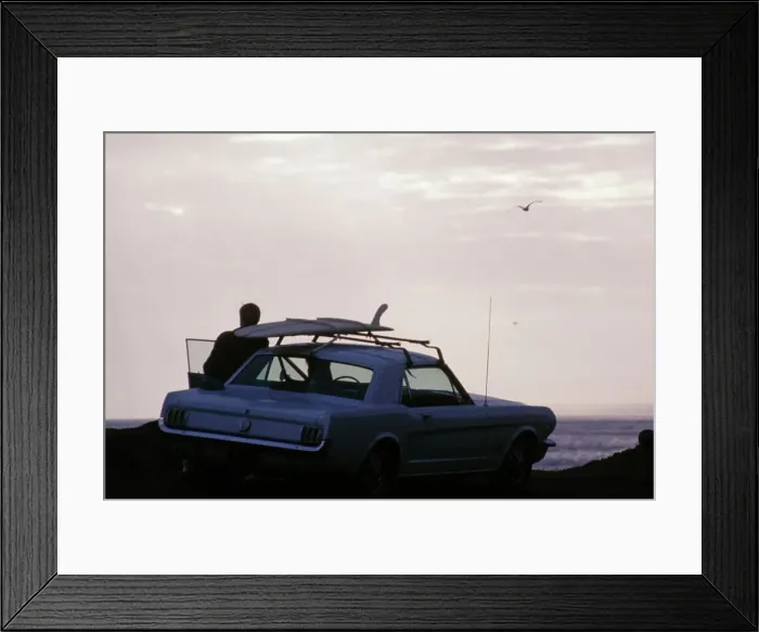 Framed Print : Surf Car. A man leaning against a car with a surfboard mounted on the roof Framed Print : Surf Car. A man leaning against a car with a surfboard mounted on the roof