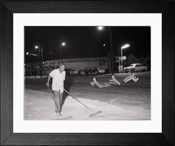 Framed Print : Man Pushing Brooms After Riot Framed Print : Man Pushing Brooms After Riot