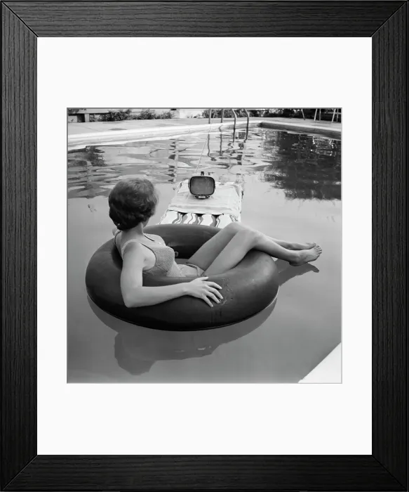 Framed Print : Young Woman Watches Television in the Pool Framed Print : Young Woman Watches Television in the Pool