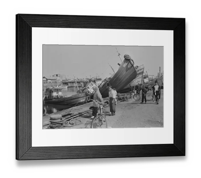 Framed Print : Woman W / Bike Looks Washed-Aground Boats