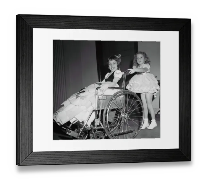 Framed Print : Girl (4-5 years) pushing friend on wheelchair. March of Dimes Fashion Show, Waldorf Astoria, Manhattan, New York City, New York State, USA. January 31, 1950 Framed Print : Girl (4-5 years) pushing friend on wheelchair. March of Dimes Fashion Show, Waldorf Astoria, Manhattan, New York City, New York State, USA. January 31, 1950