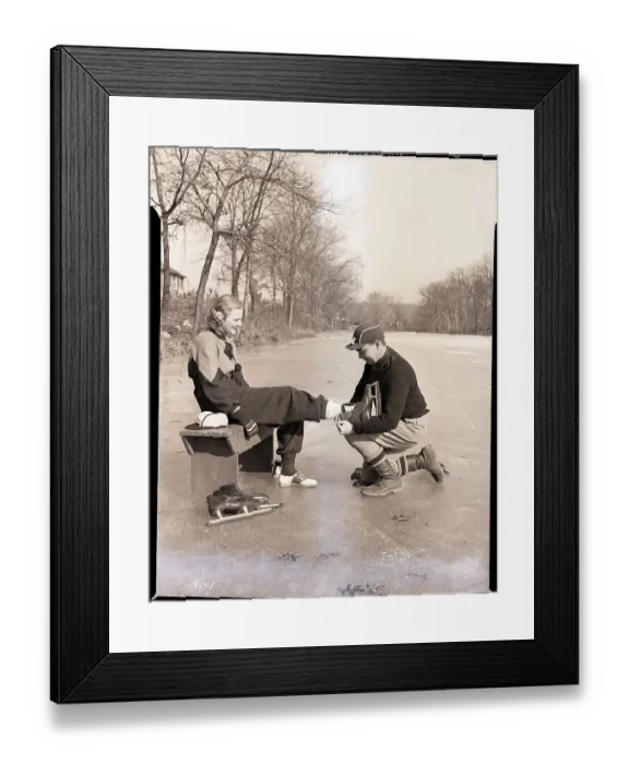 Framed Print : Man Putting on Woman's Ice Skates Framed Print : Man Putting on Woman's Ice Skates