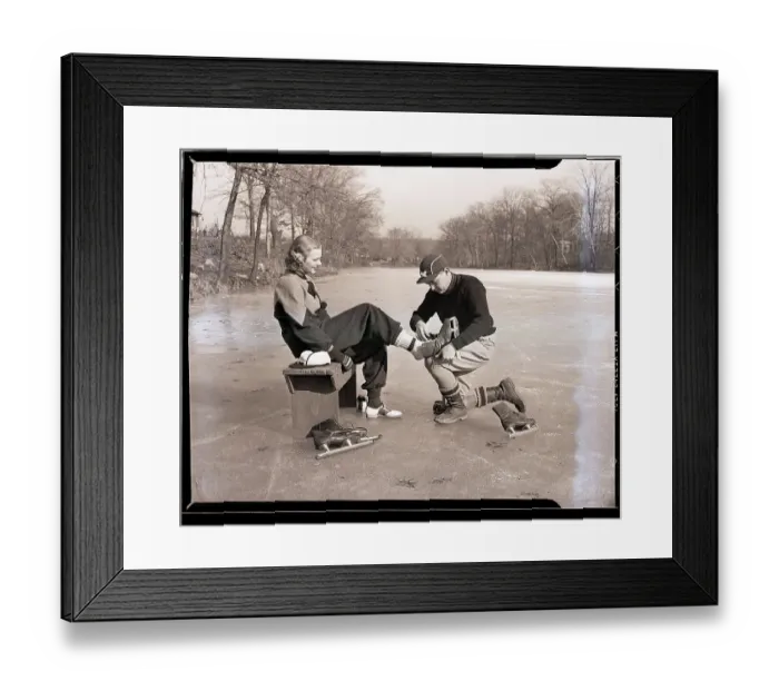 Framed Print : Man Putting on Woman's Ice Skates Framed Print : Man Putting on Woman's Ice Skates