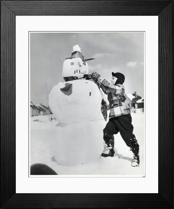 Framed Print : Boy Tying Scarf Around Snowman Framed Print : Boy Tying Scarf Around Snowman