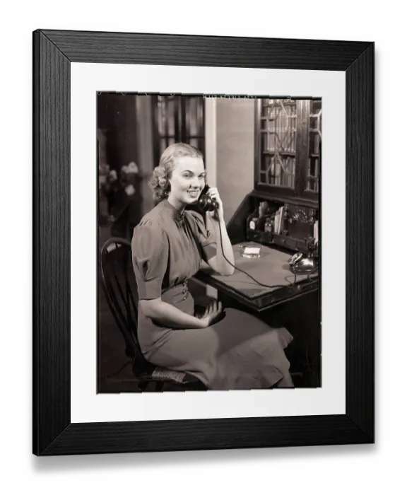 Framed Print : Woman Seated at Desk Talking on Phone Framed Print : Woman Seated at Desk Talking on Phone