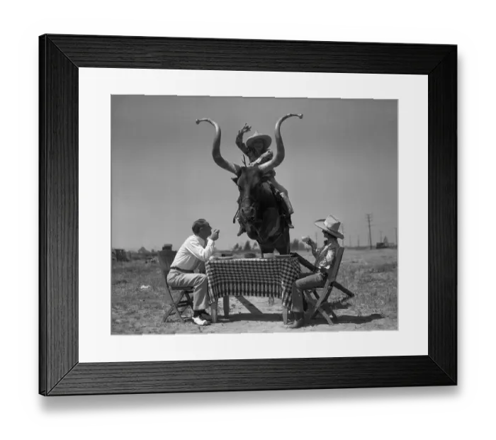 Framed Print : Men having coffee when woman jumping on bull over table Framed Print : Men having coffee when woman jumping on bull over table