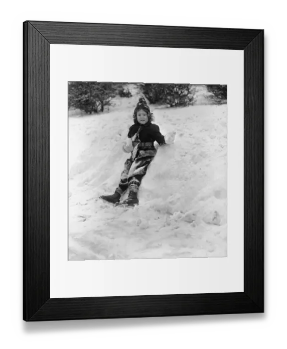 Framed Print : Portrait of girl (6-7) sitting on snow Framed Print : Portrait of girl (6-7) sitting on snow
