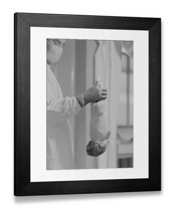 Framed Print : Doctor Holds New Born Baby by his Feet Framed Print : Doctor Holds New Born Baby by his Feet