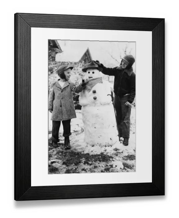 Framed Print : Two boys (8-9) posing with snowman