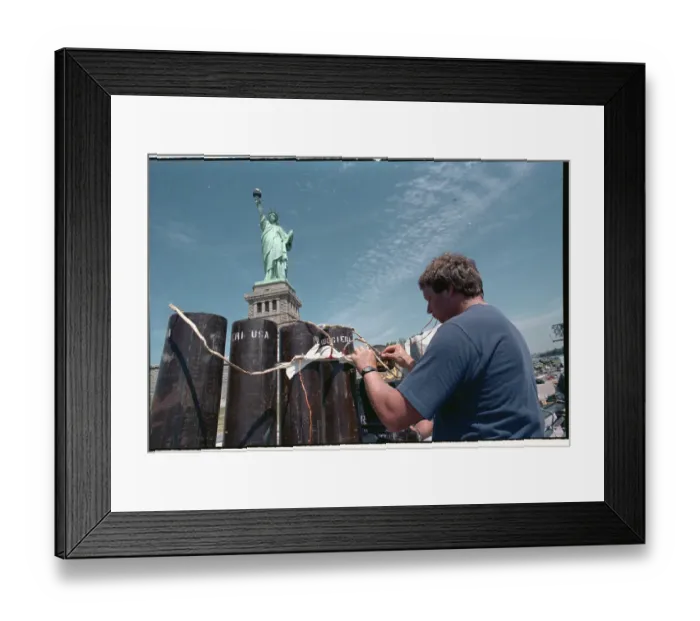 Framed Print : Man Working on Fence near Statue of Liberty