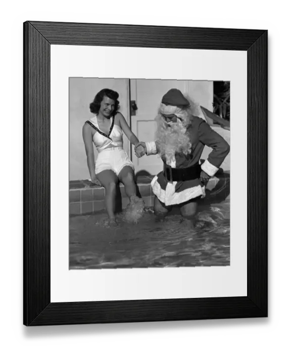 Framed Print : Woman with Man Dressed as Santa Wading in Pool Framed Print : Woman with Man Dressed as Santa Wading in Pool