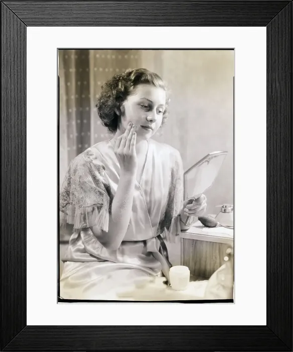 Framed Print : Woman Holding Mirror and Applying Cream Framed Print : Woman Holding Mirror and Applying Cream