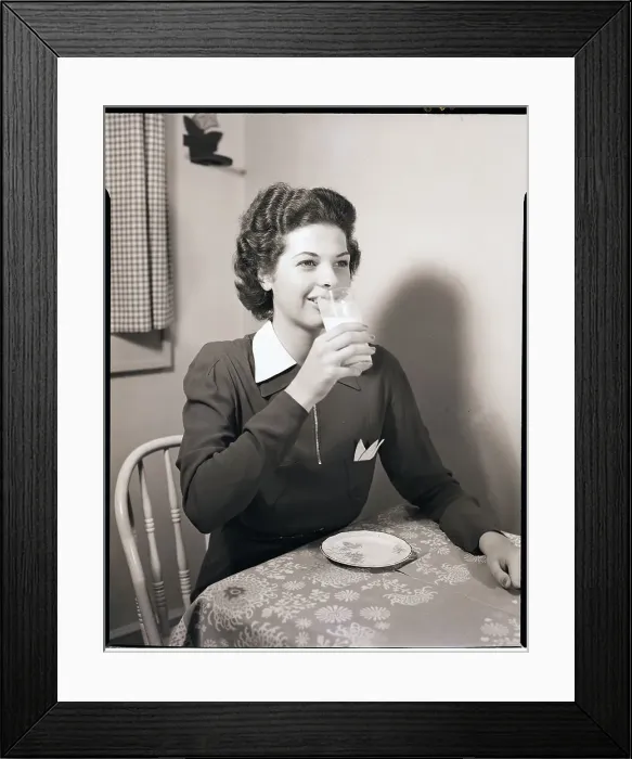 Framed Print : Woman Drinks Milk from Glass at Table Framed Print : Woman Drinks Milk from Glass at Table