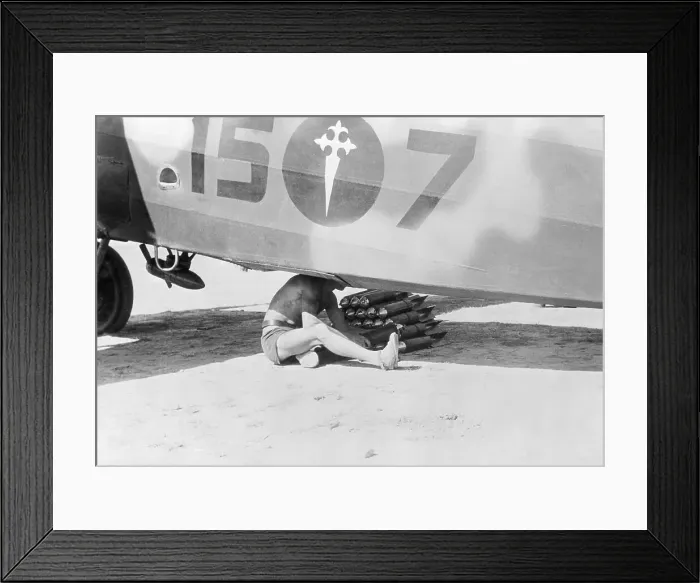 Framed Print : Man Loading Bombs into Base of Airplane Framed Print : Man Loading Bombs into Base of Airplane