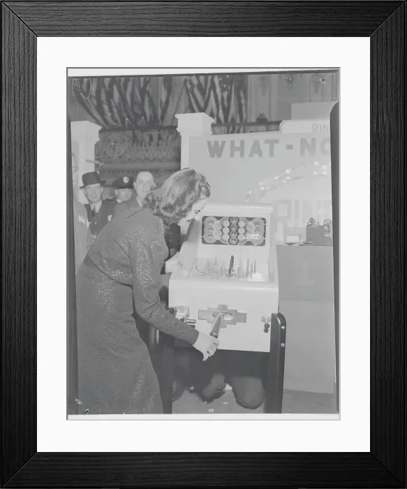 Framed Print : Young Woman Testing Coin Machinery for Game at Exhibit Framed Print : Young Woman Testing Coin Machinery for Game at Exhibit