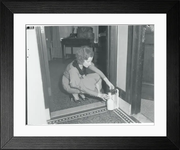 Framed Print : Young Woman Retrieving Her Protected Milk from Doorstep Framed Print : Young Woman Retrieving Her Protected Milk from Doorstep