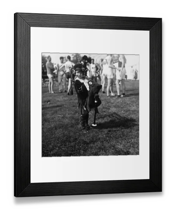 Framed Print : Little Girl (2-3 years) Playing Bagpipes, football players in background. Boston, Massachusetts, USA. August 04, 1925 Framed Print : Little Girl (2-3 years) Playing Bagpipes, football players in background. Boston, Massachusetts, USA. August 04, 1925