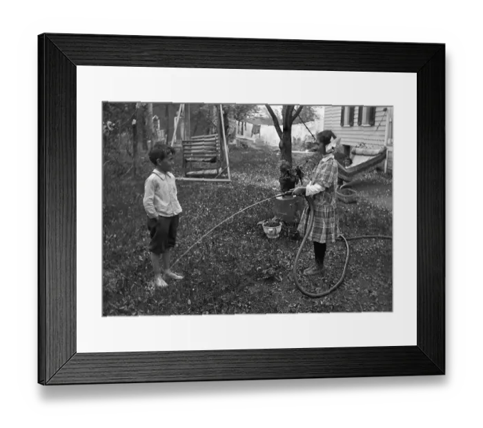 Framed Print : Children (6-7 years) playing with hose in garden Framed Print : Children (6-7 years) playing with hose in garden