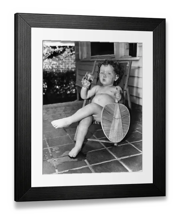 Framed Print : Girl (2-3 years ) sitting on lounge chair with drink and fan Framed Print : Girl (2-3 years ) sitting on lounge chair with drink and fan