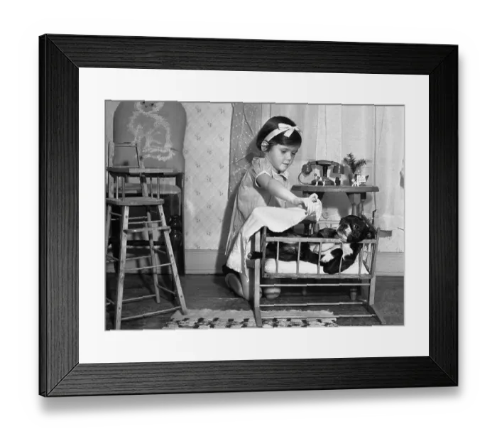 Framed Print : Girl (6-7) playing home with dog serving as baby substitute Framed Print : Girl (6-7) playing home with dog serving as baby substitute