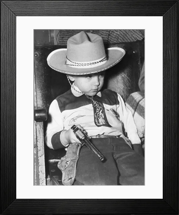 Framed Print : Portrait of boy (4-5) in cowboy costume holding pistol Framed Print : Portrait of boy (4-5) in cowboy costume holding pistol