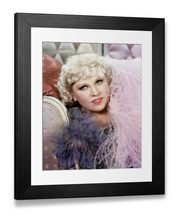 Framed Print : Mae West. Close-up of actress Mae West. She is reclining in a pink boa. Undated photograph