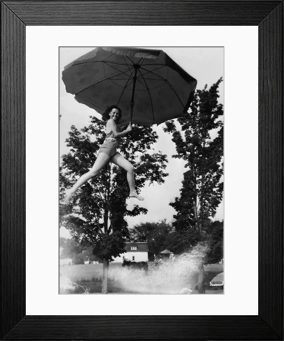 Framed Print : Young smiling woman holding umbrella in air Framed Print : Young smiling woman holding umbrella in air