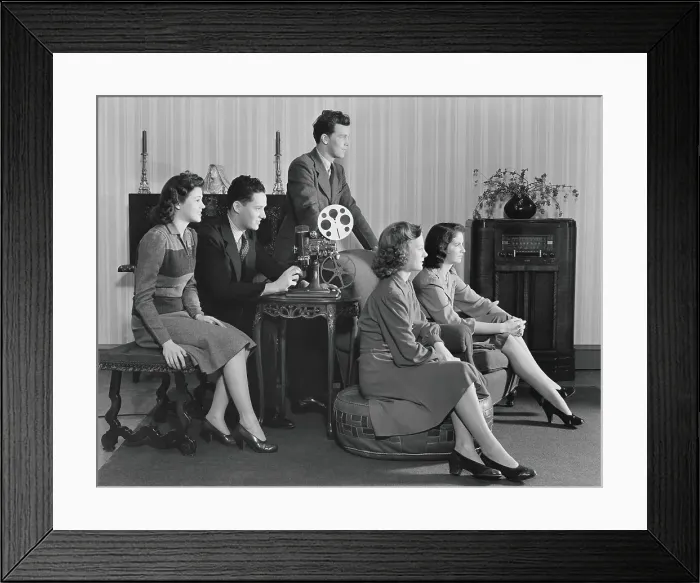 Framed Print : Five people watching home movies, seated around projector, looking toward screen