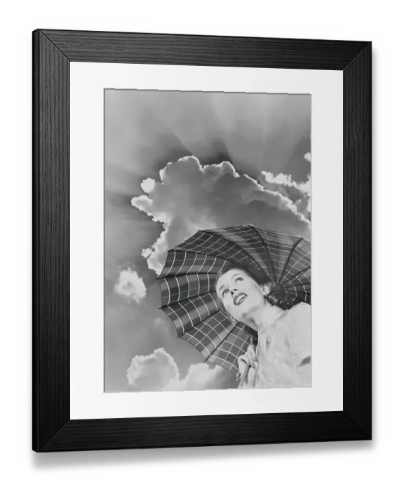 Framed Print : Woman in raincoat holding umbrella looking up into sky of dark clouds and impending storm