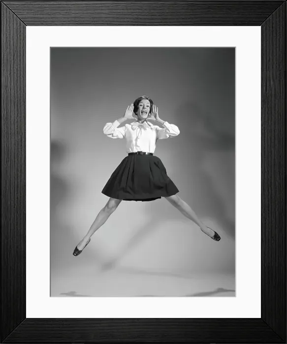 Framed Print : Woman doing cheerleader jump, hand up to mouth, yelling and screaming Framed Print : Woman doing cheerleader jump, hand up to mouth, yelling and screaming