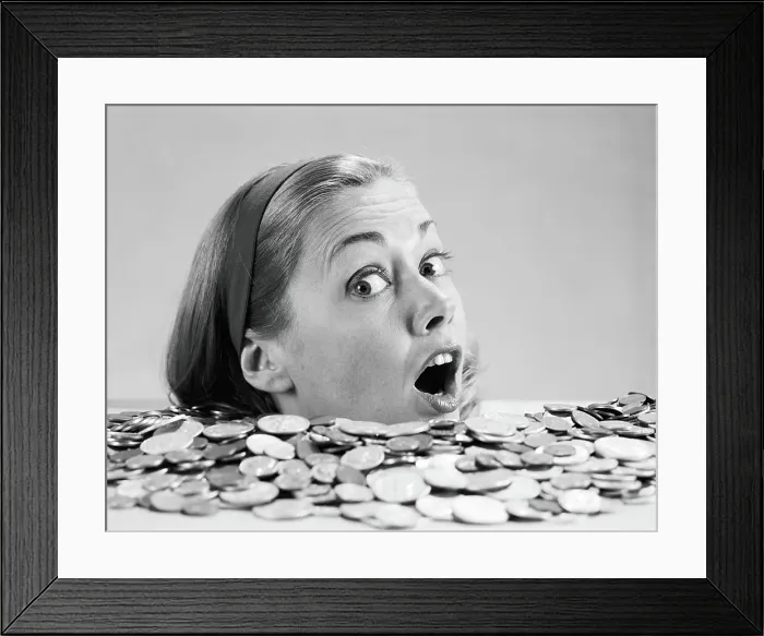Framed Print : Woman pulling funny face, up to her neck in coins Framed Print : Woman pulling funny face, up to her neck in coins