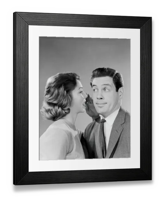 Framed Print : Woman whispering into man's ear, man pulling funny face Framed Print : Woman whispering into man's ear, man pulling funny face