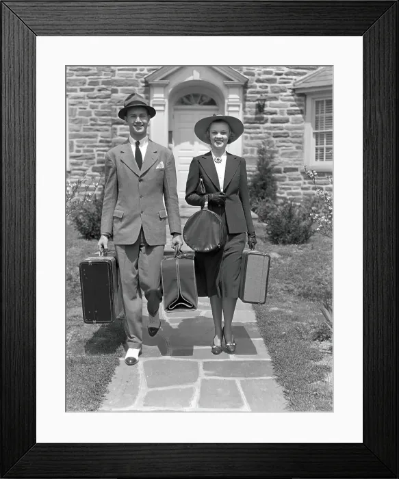 Framed Print : Couple walking along sidewalk, carrying suitcases Framed Print : Couple walking along sidewalk, carrying suitcases