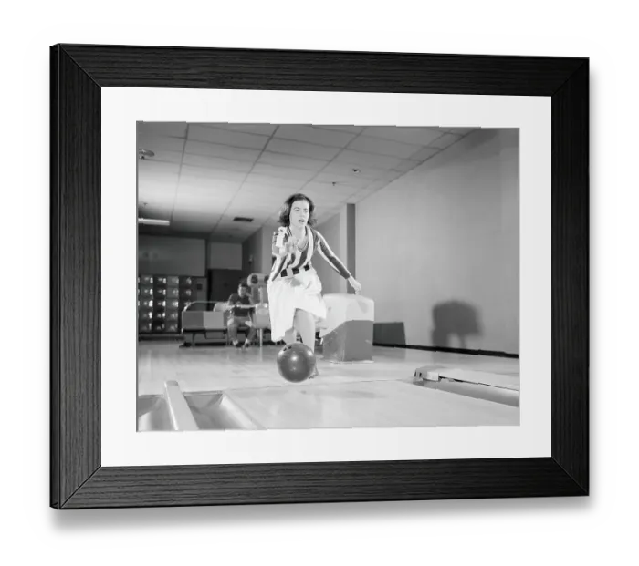 Framed Print : Teenage girl releasing bowling ball into alley, friend looking on in background Framed Print : Teenage girl releasing bowling ball into alley, friend looking on in background