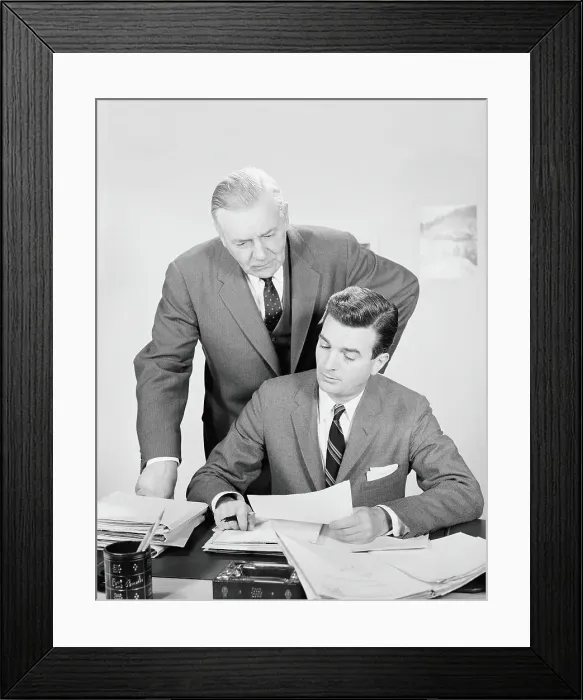 Framed Print : Businessman sitting at desk, with boss looking over shoulder, reviewing paperwork Framed Print : Businessman sitting at desk, with boss looking over shoulder, reviewing paperwork