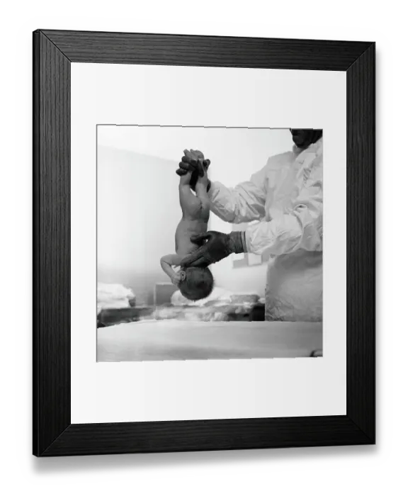 Framed Print : Doctor holding newborn baby upside-down by it's ankles slapping it's bottom to start it breathing, rear view Framed Print : Doctor holding newborn baby upside-down by it's ankles slapping it's bottom to start it breathing, rear view