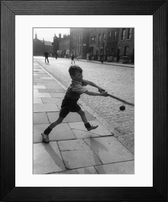 Framed Print : Ball Game. 7th August 1954: A young boy playing an improvised game of cricket with a bat Framed Print : Ball Game. 7th August 1954: A young boy playing an improvised game of cricket with a bat