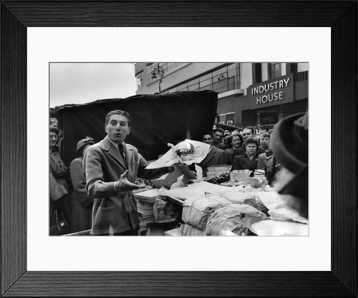 Framed Print : Bad Taste. circa 1951: A street trader offers a teapot at a market in front Framed Print : Bad Taste. circa 1951: A street trader offers a teapot at a market in front