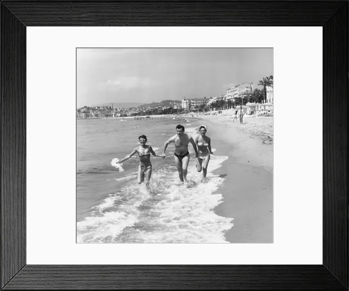 Framed Print : Cannes. May 1956: George Baker runs through the surf at Cannes with Bella Darvi Framed Print : Cannes. May 1956: George Baker runs through the surf at Cannes with Bella Darvi