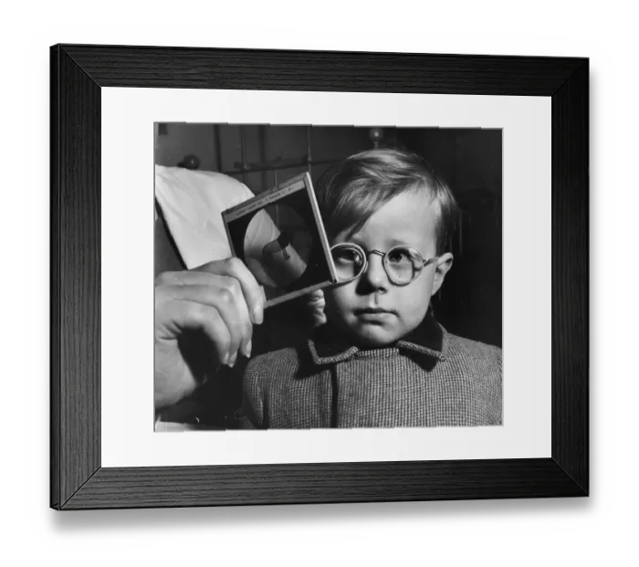 Framed Print : Eye Test. 1955: A young boy's eyesight is examined using a glass picture test card Framed Print : Eye Test. 1955: A young boy's eyesight is examined using a glass picture test card