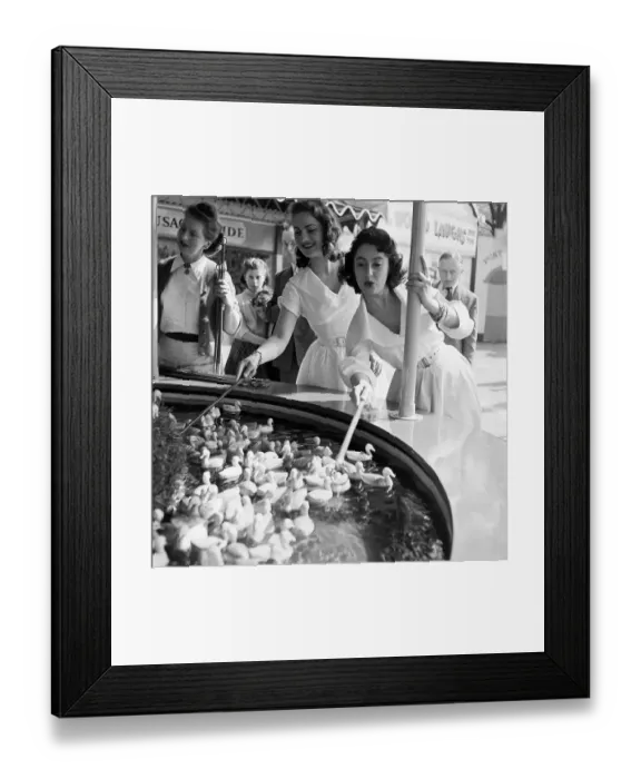 Framed Print : Duck Hook. 20th June 1953: Two young women hooking floating ducks at a