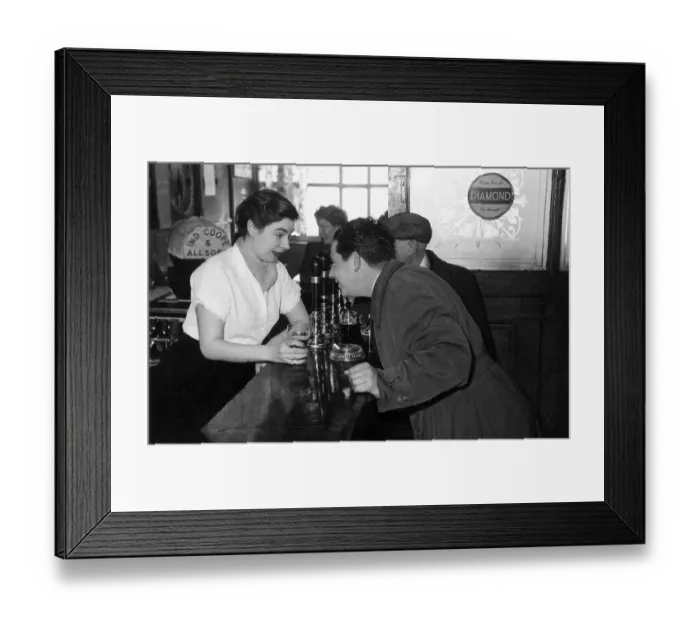 Framed Print : Bar Chat. 27th December 1952: A barmaid enjoys a drink and a chat with a customer in a pub
