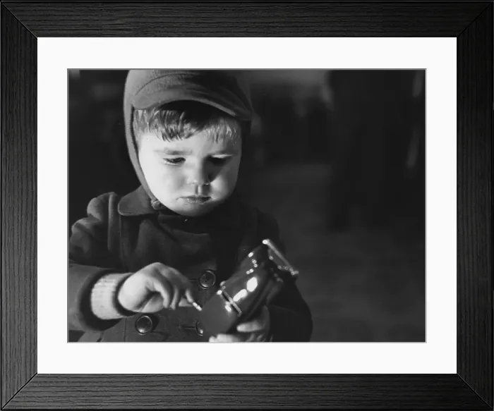 Framed Print : Model Car. December 1949: A young boy winding up the model motor car which Framed Print : Model Car. December 1949: A young boy winding up the model motor car which