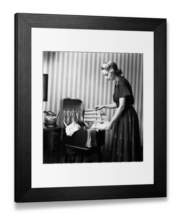 Framed Print : Flat Hat. 30th July 1949: A woman unhooks the petersham headband of a mauve hat Framed Print : Flat Hat. 30th July 1949: A woman unhooks the petersham headband of a mauve hat