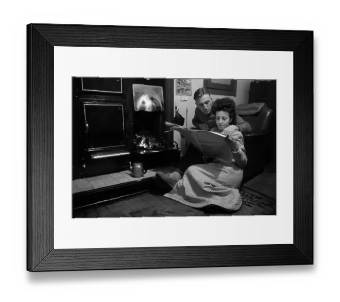 Framed Print : Memories. 4th January 1947: A couple read a paper in front of a coal fire Framed Print : Memories. 4th January 1947: A couple read a paper in front of a coal fire